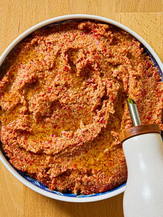 Un bol de muhammara arrosé d'huile d'olive sur une surface en bois