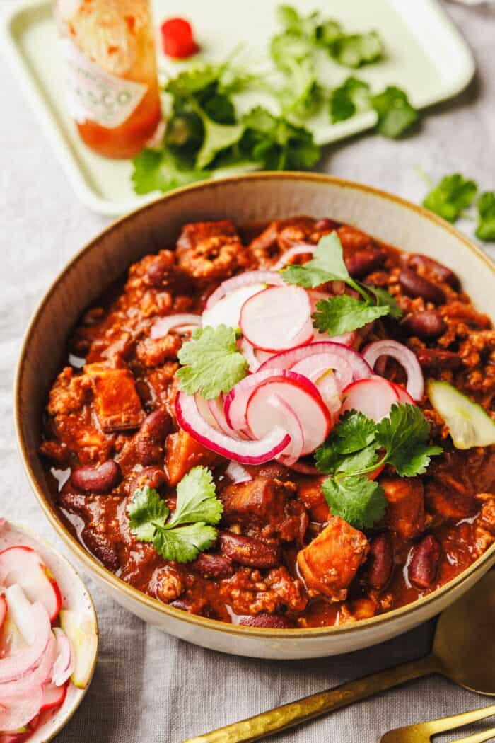 Chili de patate douce végétalien avec haricots rouges et garniture de cornichons